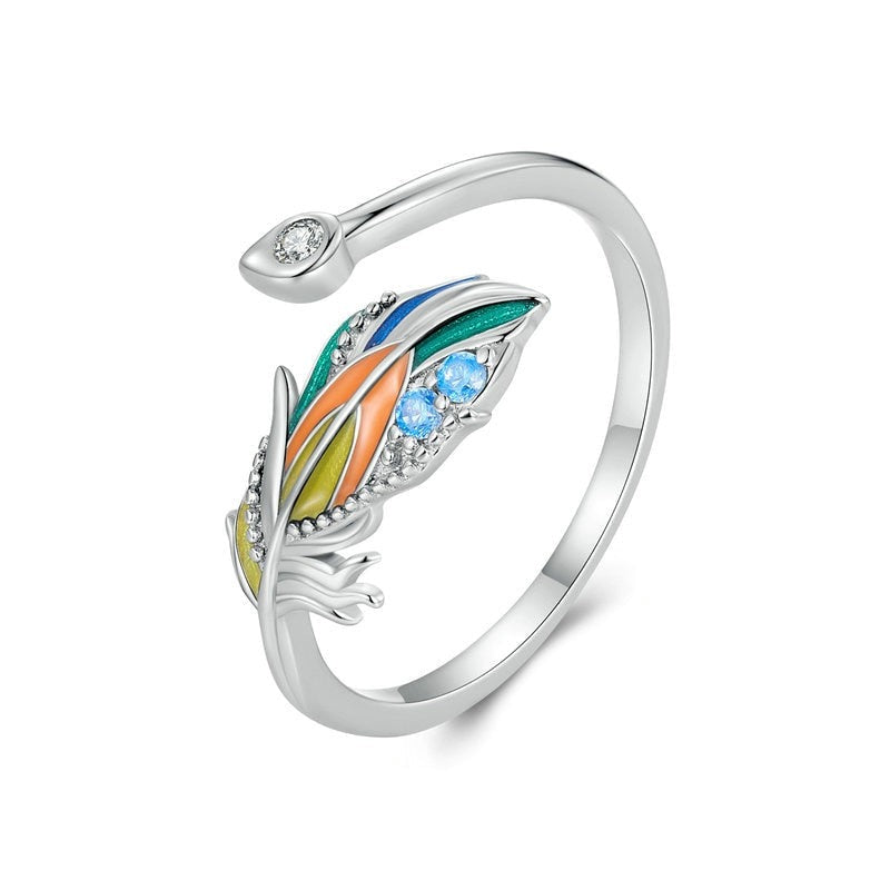 Um anel de prata 925 com uma pena colorida e pedras brilhantes na parte superior, visto de cima.